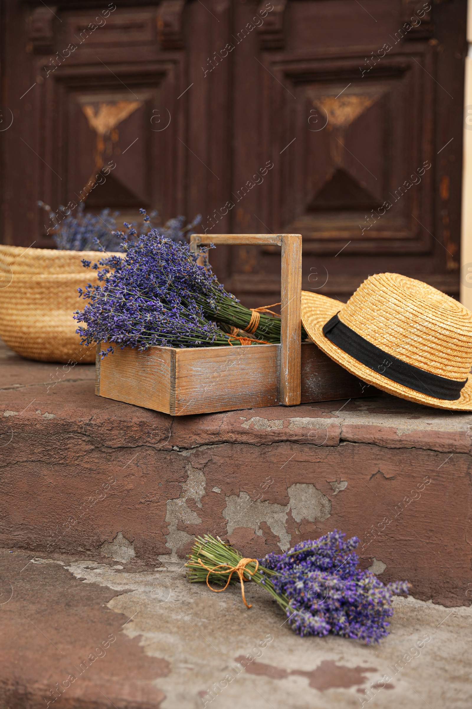 Photo of Beautiful lavender flowers and straw hat near building outdoors