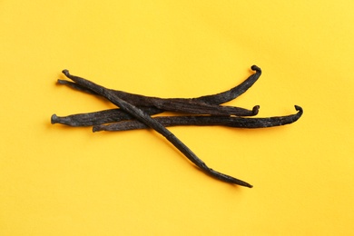 Photo of Bunch of aromatic vanilla sticks on yellow background