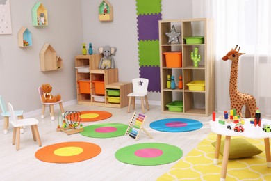 Child`s playroom with different toys and furniture. Cozy kindergarten interior