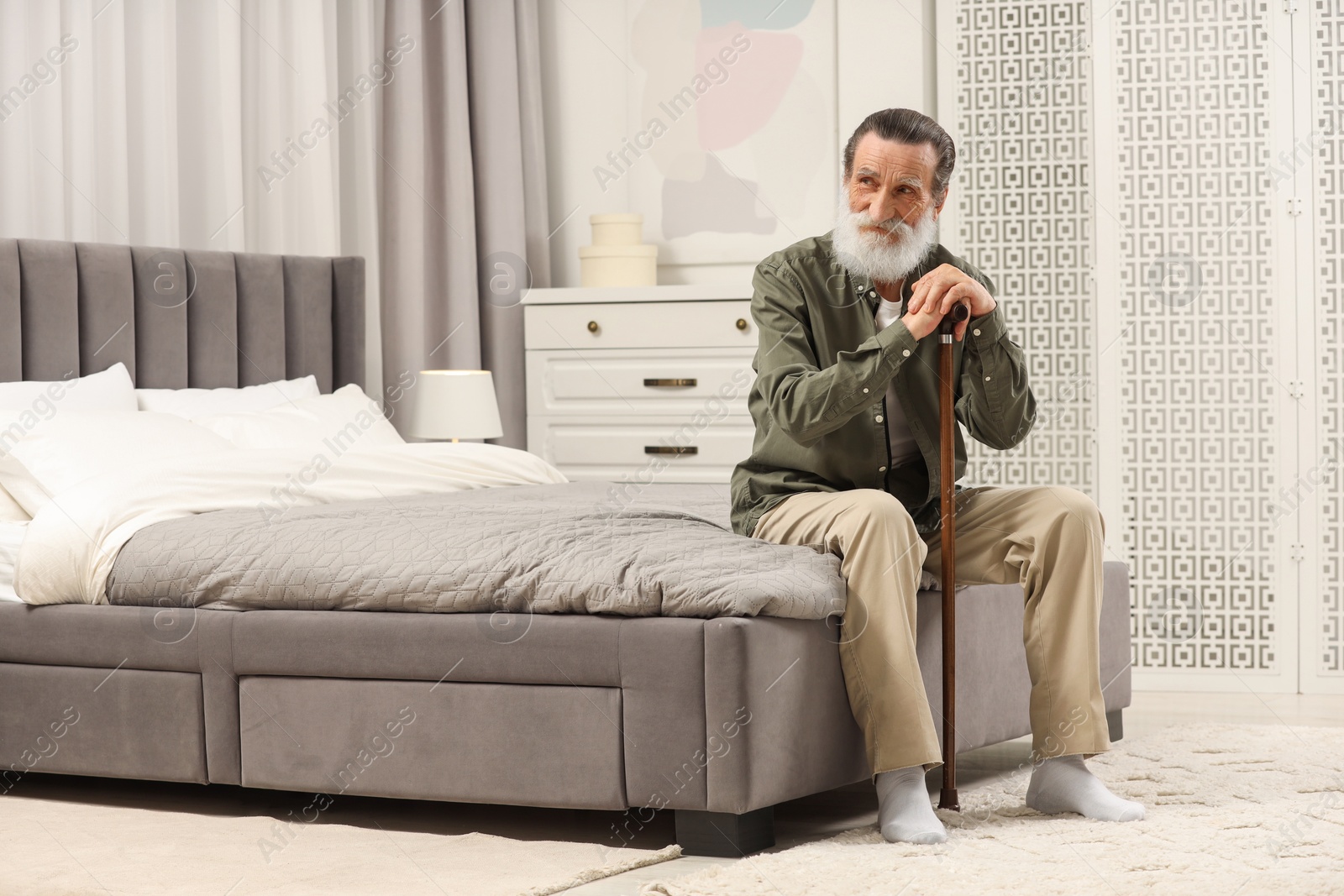 Photo of Senior man with walking cane on bed at home