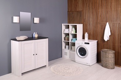 Photo of Laundry room interior with washing machine near wall