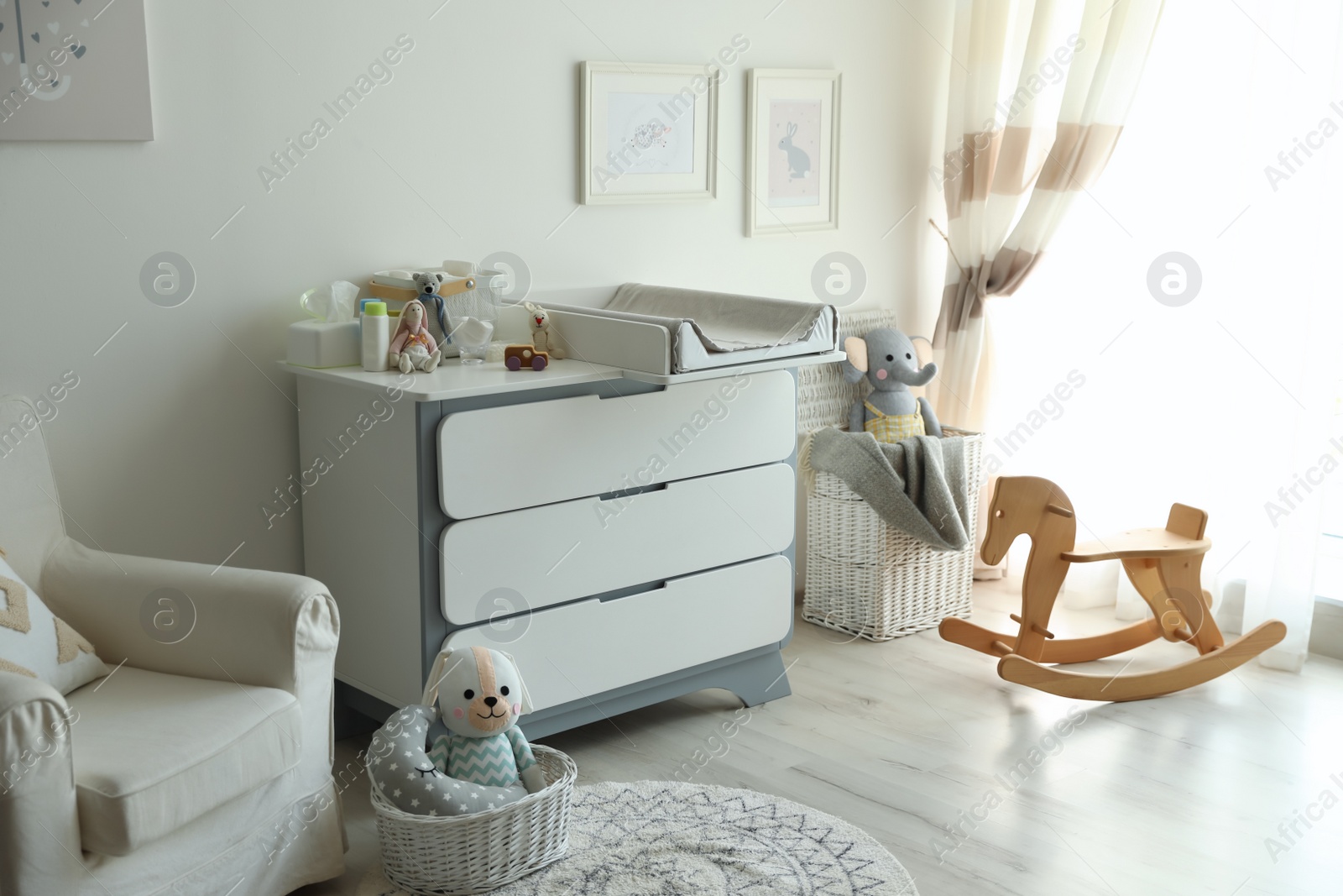 Photo of Beautiful baby room interior with toys, armchair and modern changing table