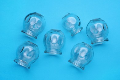 Photo of Glass cups on light blue background, flat lay. Cupping therapy