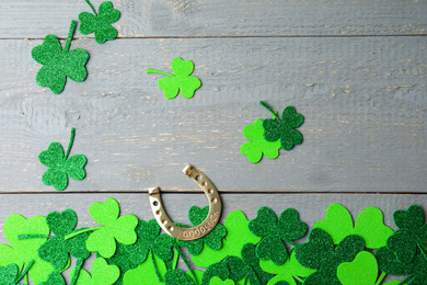 Photo of Flat lay composition with clover leaves and horseshoe on light grey wooden background. St. Patrick's day