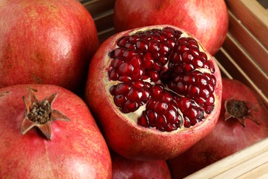 Photo of Fresh ripe pomegranates in wooden crate, closeup