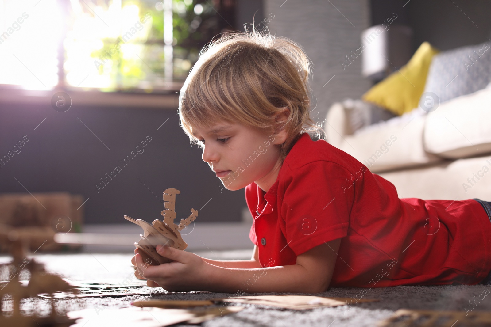 Photo of Little boy making cardboard toys on floor at home. Creative hobby