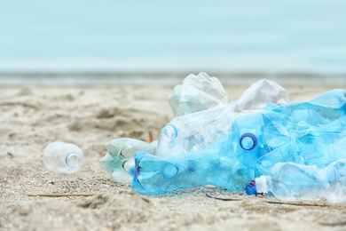 Used plastic bottles on beach, space for text. Recycling problem