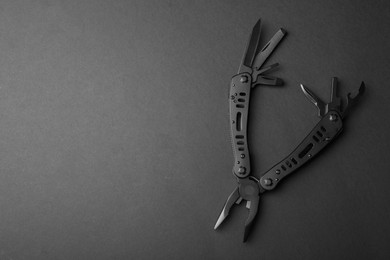 Photo of Compact portable multitool on black background, top view. Space for text