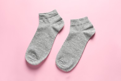 Photo of Pair of grey socks on pink background, flat lay