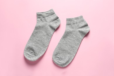 Pair of grey socks on pink background, flat lay