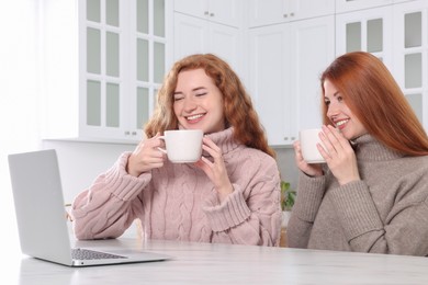 Photo of Beautiful young sisters spending time together in kitchen