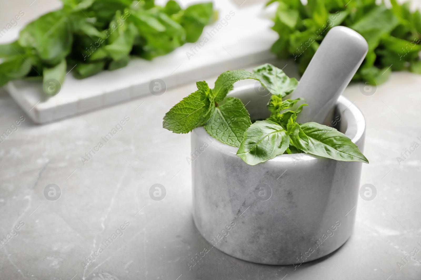 Photo of Mortar with fresh green herbs on table