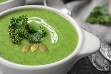 Tasty kale soup with pumpkin seeds on grey table, closeup