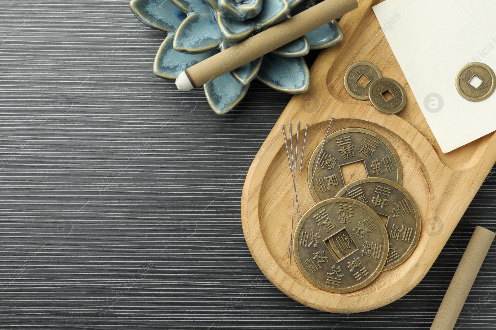 Photo of Acupuncture needles, moxa sticks and antique Chinese coins on wooden table, flat lay. Space for text
