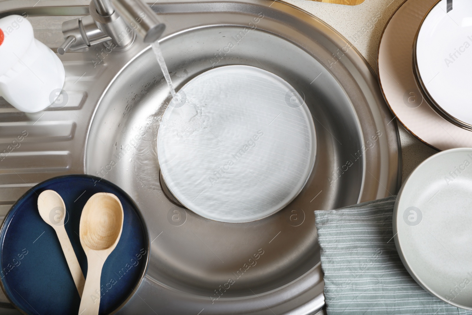 Photo of Washing plate in kitchen sink, above view