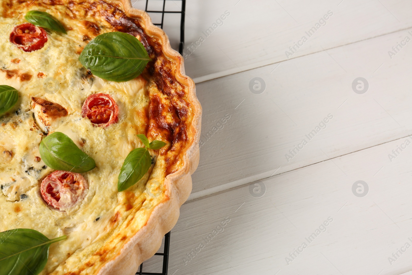 Photo of Delicious homemade cheese quiche on white wooden table, closeup. Space for text