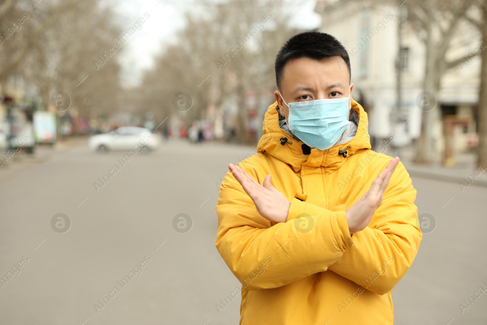 Photo of Asian man wearing medical mask on city street, space for text. Virus outbreak