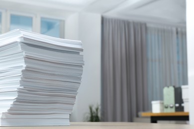Photo of Stack of paper sheets on wooden table indoors. Space for text