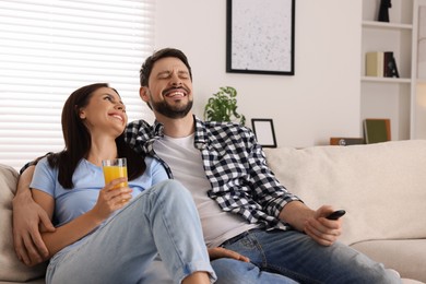 Photo of Couple watching comedy via TV and laughing at home