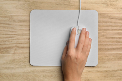 Photo of Woman using wired computer mouse on wooden table, top view. Space for text