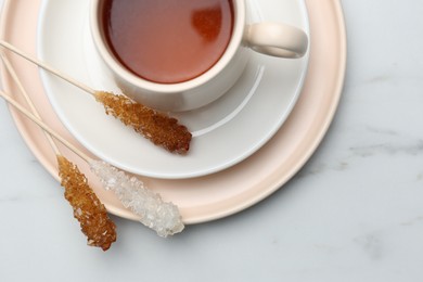 Photo of Sticks with sugar crystals served to tea on white marble table, top view