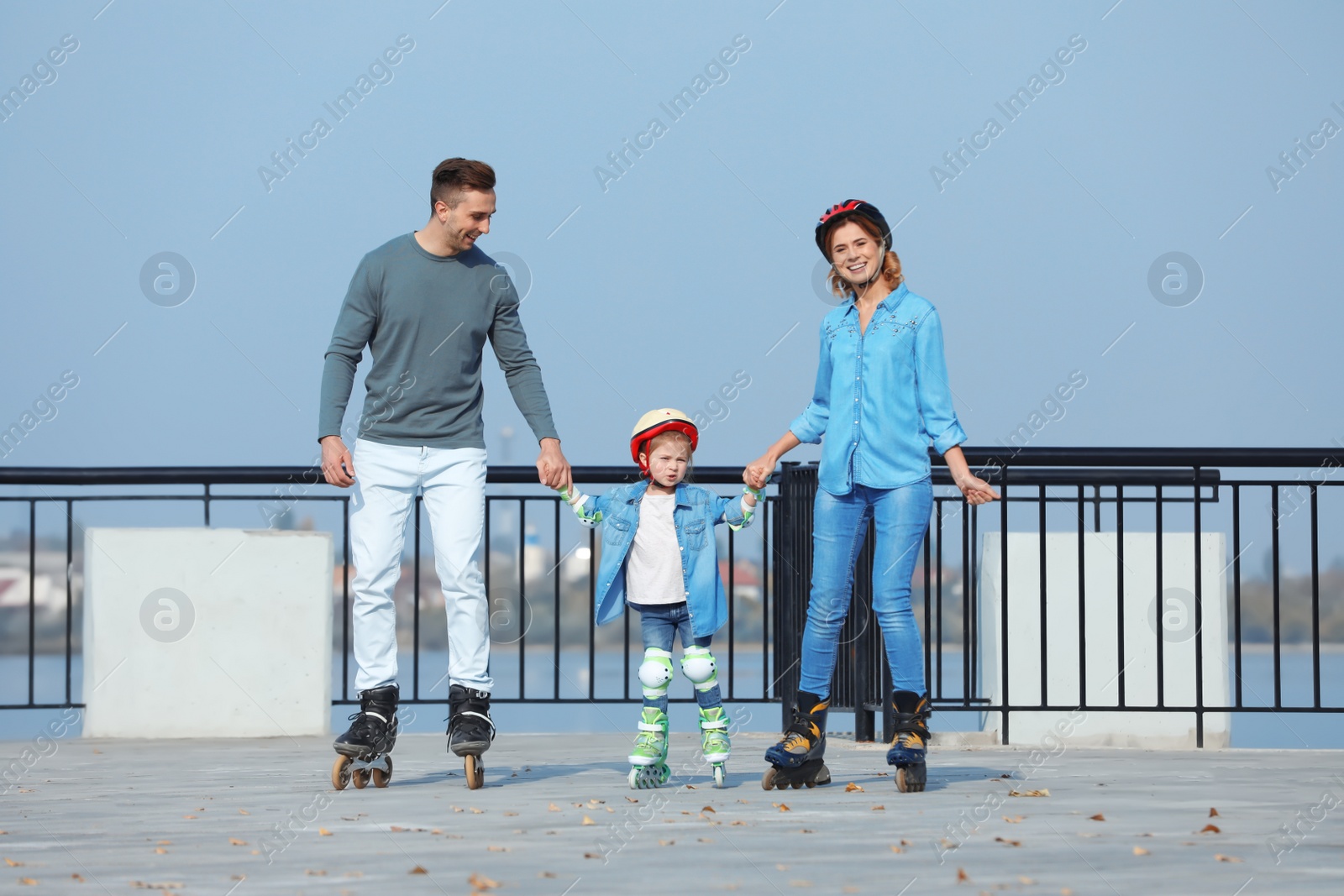 Photo of Happy family roller skating on embankment. Active leisure