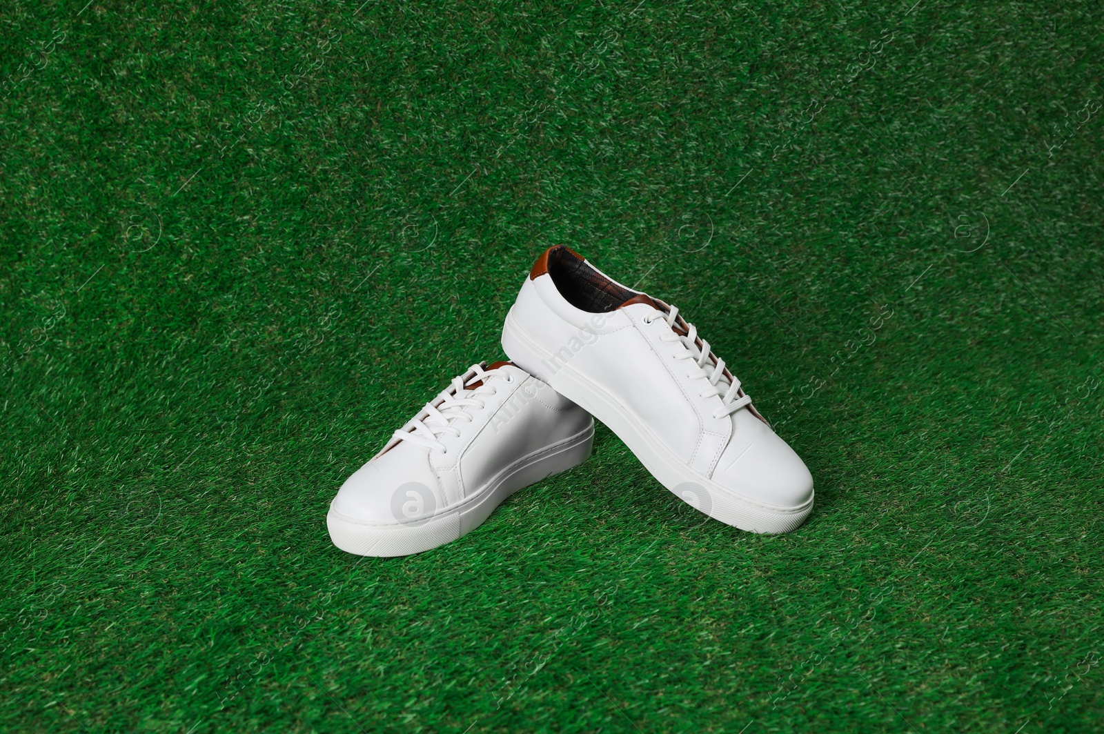 Photo of Pair of stylish sports shoes on green grass