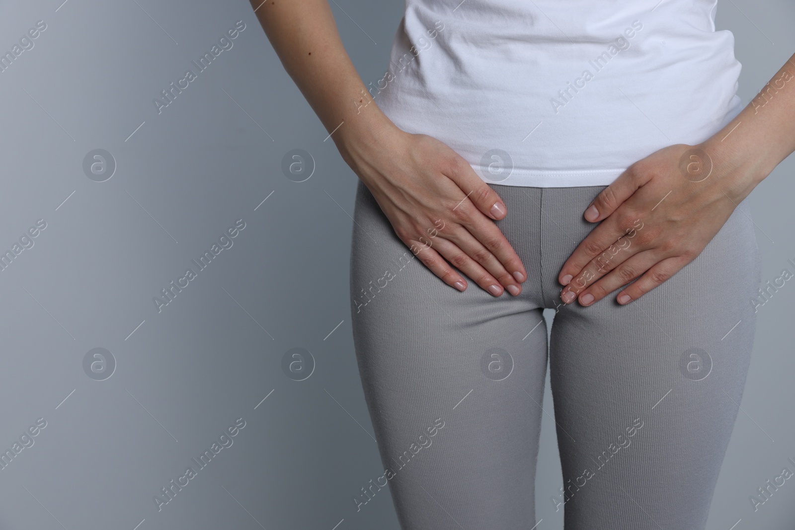 Photo of Woman suffering from herpes genital on grey background, closeup. Space for text