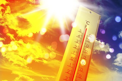 Image of Thermometer showing high temperature against sky with clouds during very hot day in summer