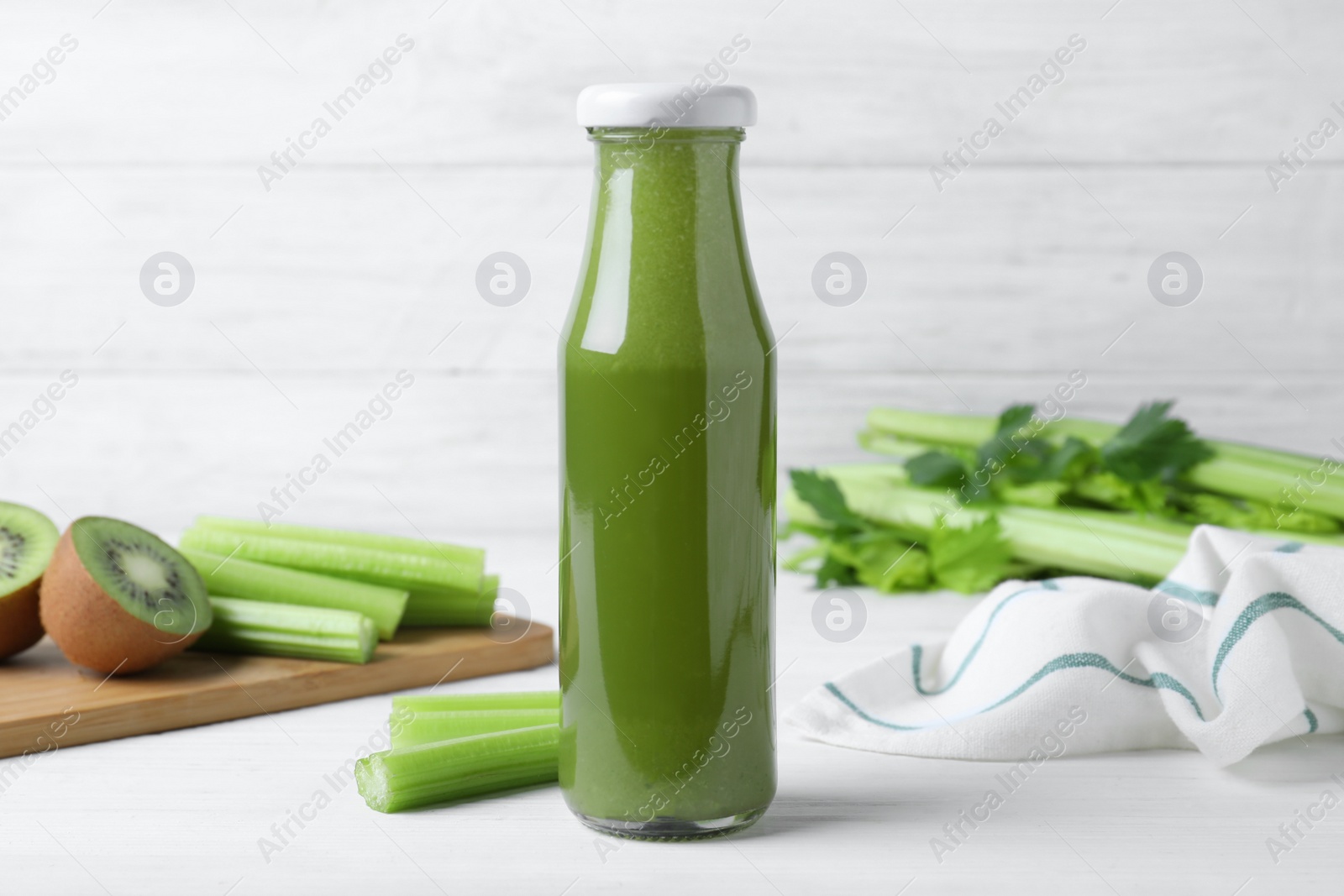 Photo of Bottle of fresh celery juice on white wooden table