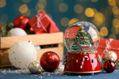 Photo of Beautiful snow globe and Christmas decor on blue table