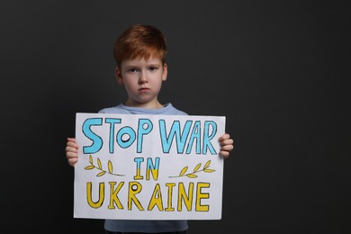 Photo of Boy holding poster Stop War in Ukraine against black background
