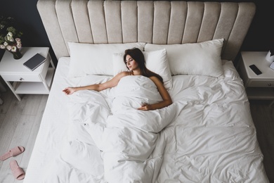 Photo of Tired woman sleeping in bed at home, above view