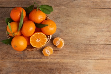 Photo of Delicious tangerines with leaves on wooden table, top view. Space for text