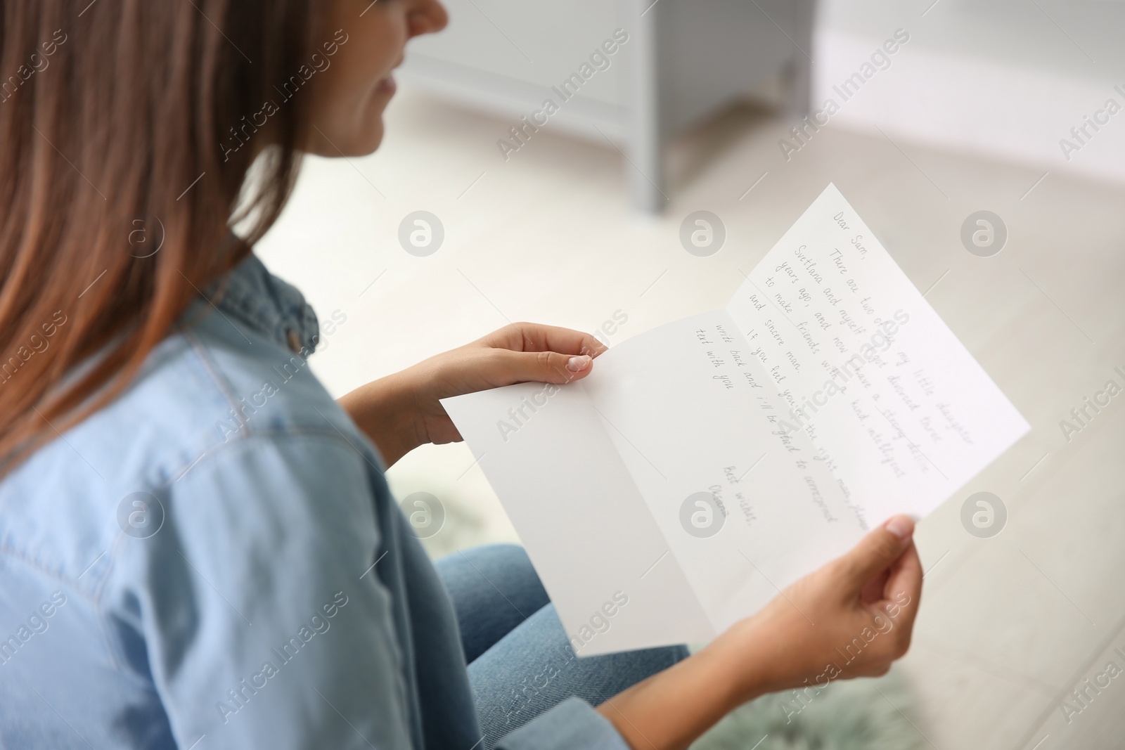 Photo of Young woman reading paper letter at home, closeup