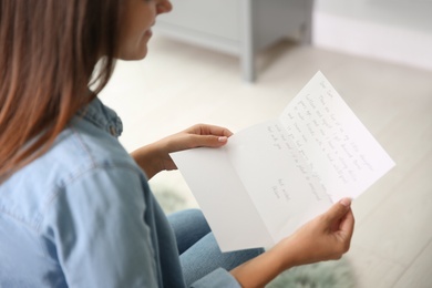 Young woman reading paper letter at home, closeup