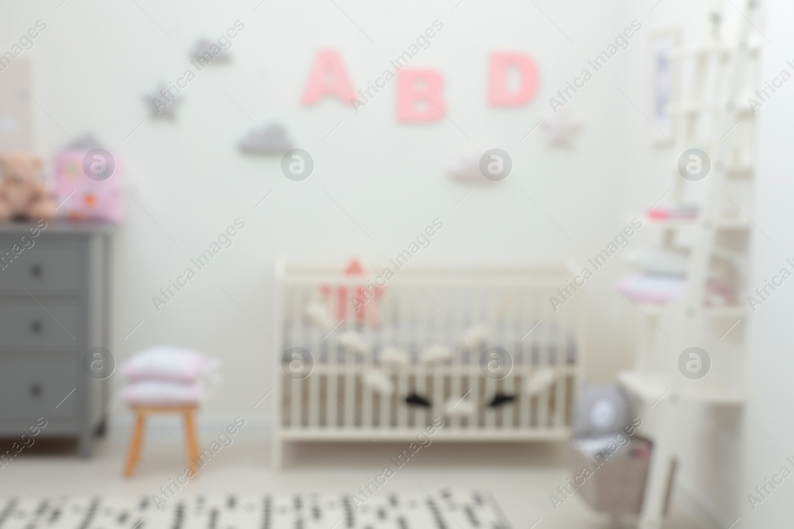 Photo of Blurred view of cute baby room interior with modern crib near white wall