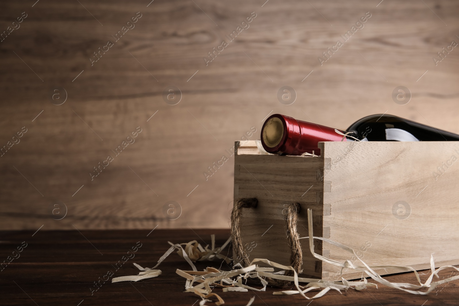 Photo of Open wooden crate with bottle of wine on table, space for text