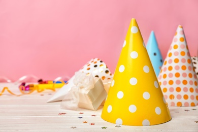 Photo of Birthday party caps on table against color background