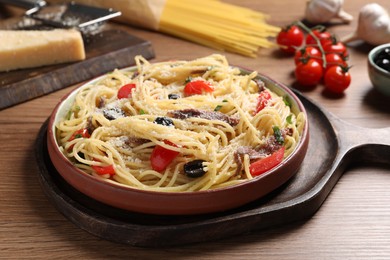 Photo of Plate of delicious pasta with anchovies and ingredients on wooden table