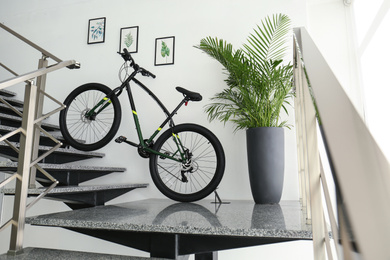Photo of Modern black bicycle on stairs at home