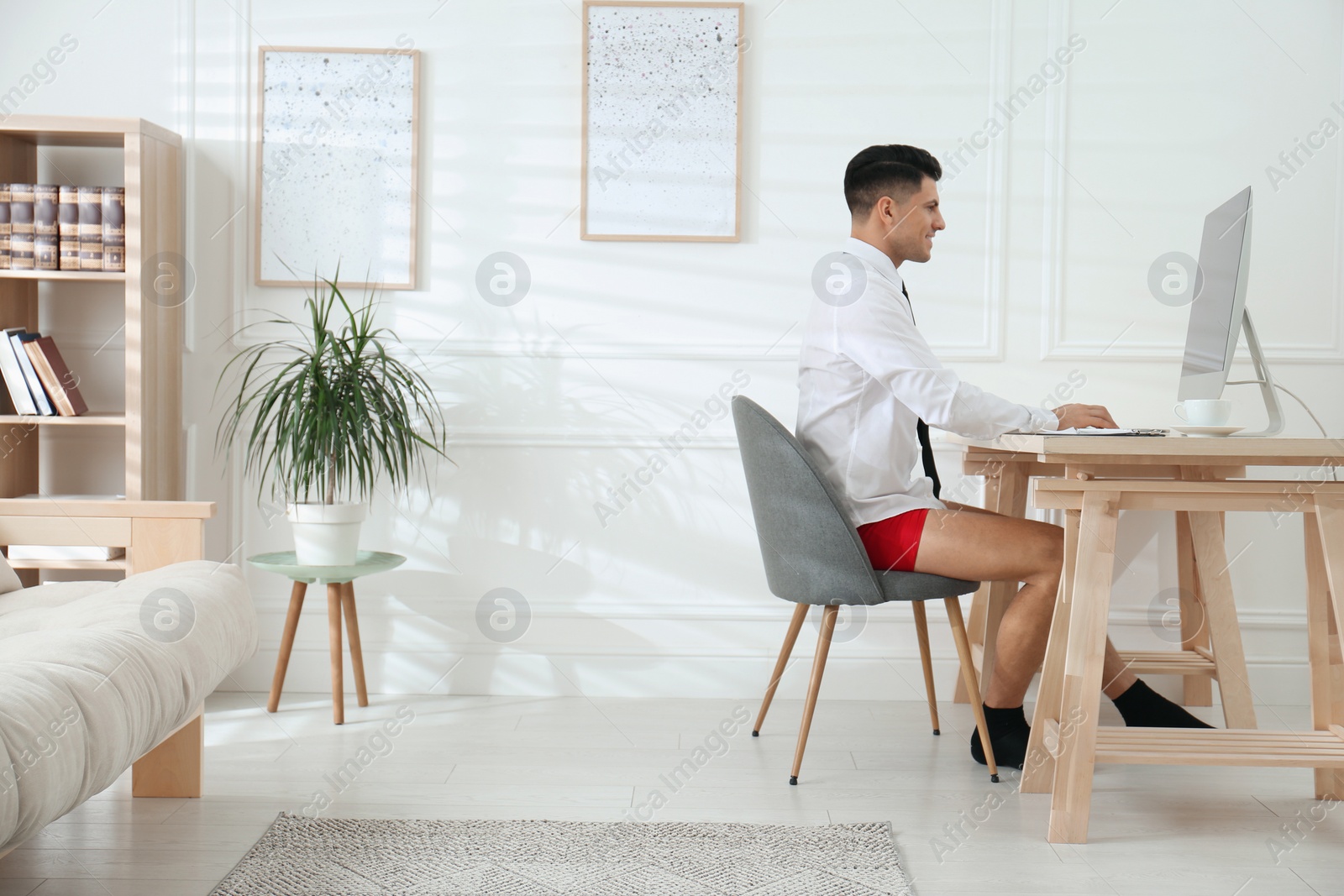 Photo of Businessman in shirt and underwear working on computer at home office