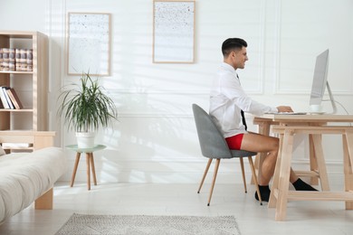 Businessman in shirt and underwear working on computer at home office