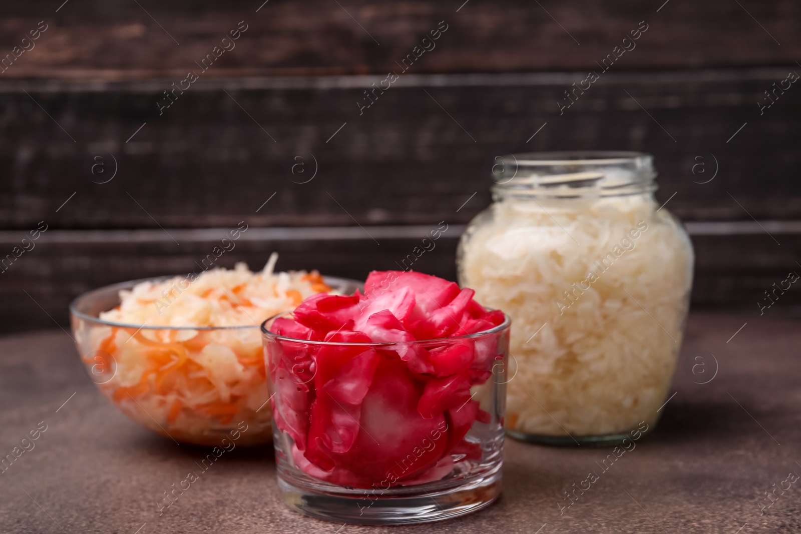 Photo of Delicious sauerkraut prepared according to different recipes on brown table