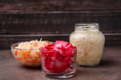 Photo of Delicious sauerkraut prepared according to different recipes on brown table