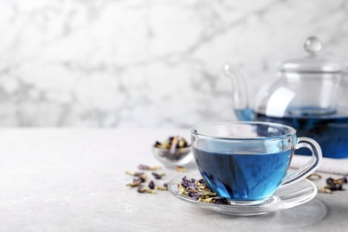 Photo of Glass cup of organic blue Anchan on light table, space for text. Herbal tea