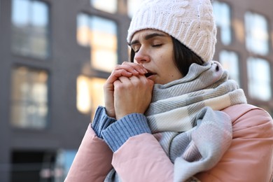 Photo of Sick young woman coughing outdoors. Cold symptom