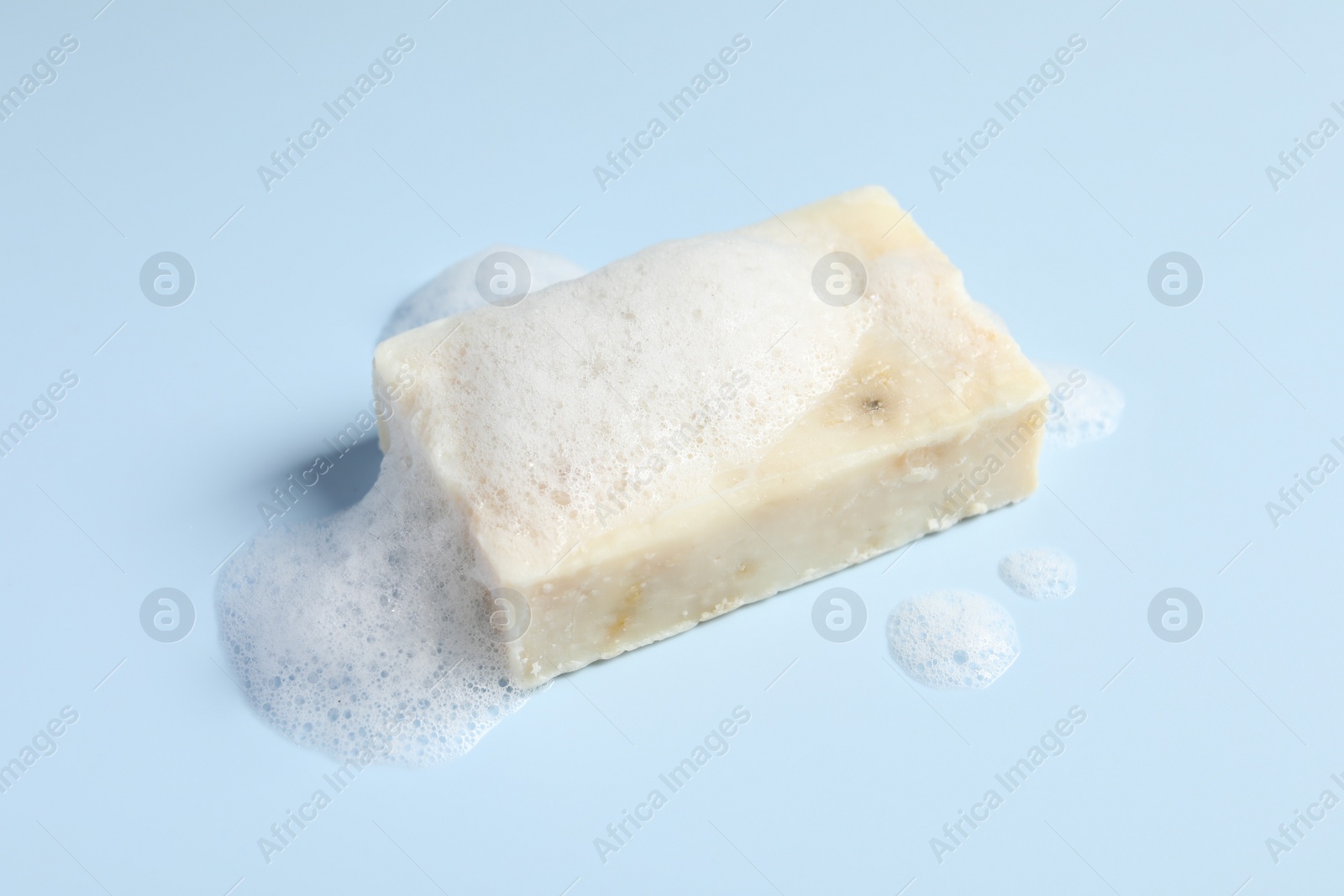 Photo of Soap with fluffy foam on light blue background