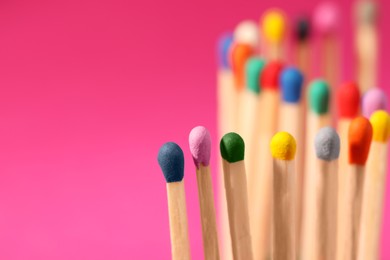 Matches with colorful heads on pink background, closeup. Space for text