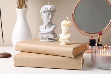 Photo of Beautiful David bust candles and books on white dressing table